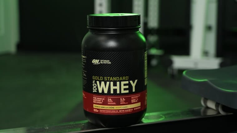 “Optimum Nutrition Gold Standard Whey tub on a gym bench